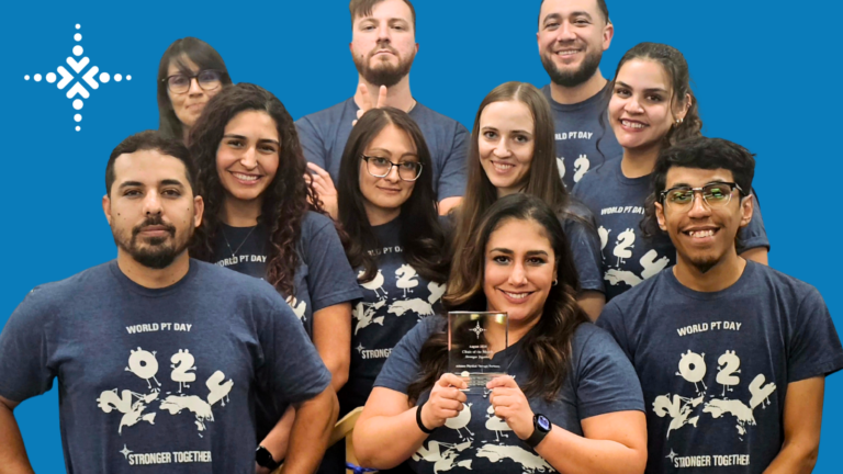 A group of employees in matching shirts holding a trophy